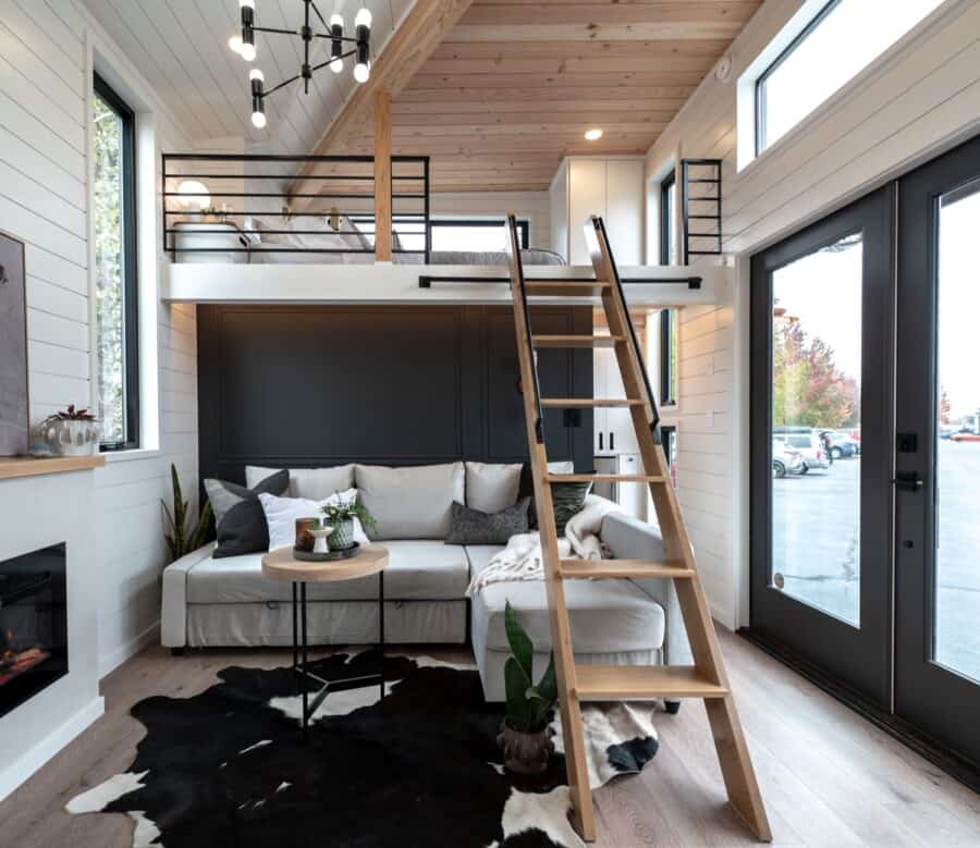 Cozy tiny house interior with loft, modern decor, and large windows for natural light.