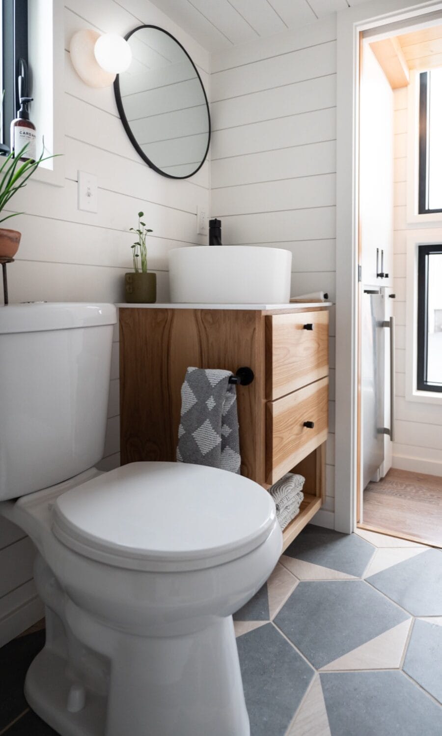 Modern tiny house bathroom with white shiplap walls and compact vanity.