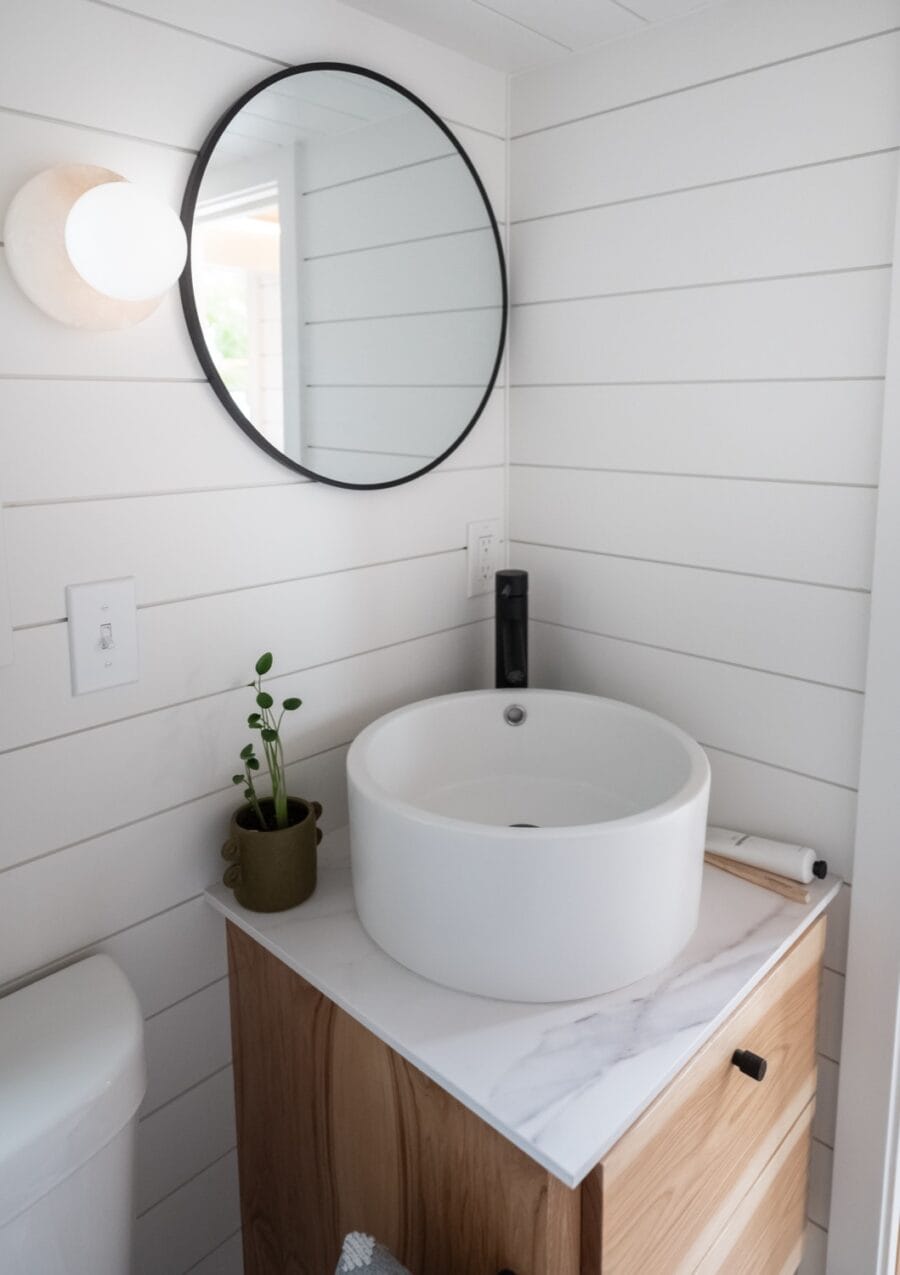 Modern tiny house bathroom with round vessel sink and minimalist decor.