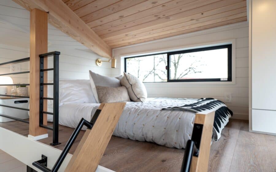 Compact tiny house bedroom with modern design and large window for natural light.