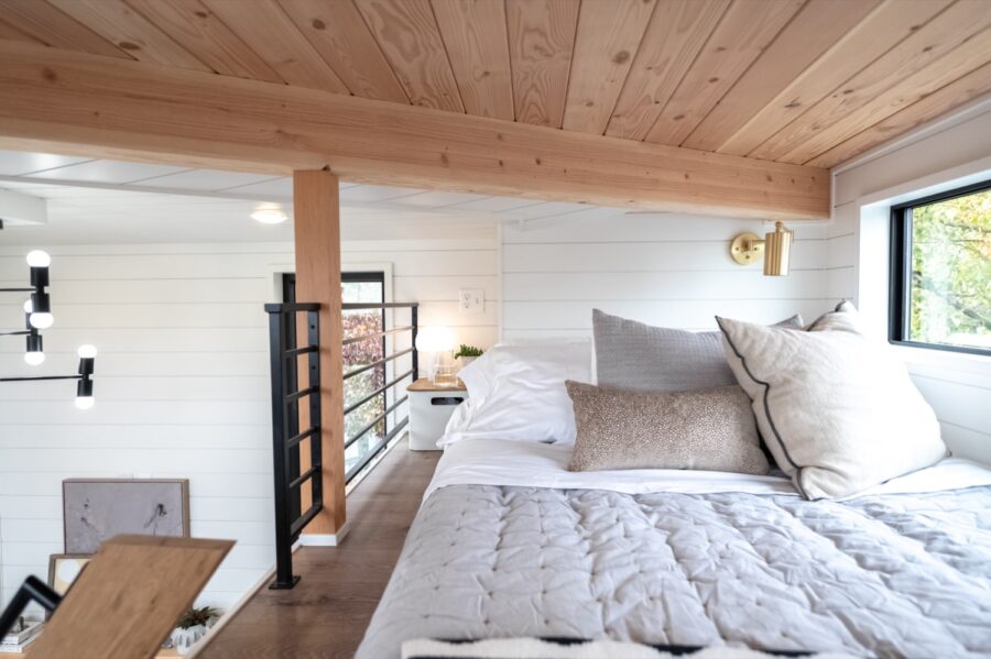 Cozy bedroom in a modern tiny house with natural wood accents and large window views.