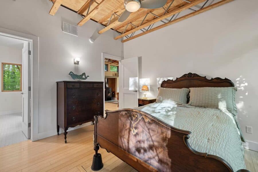 Cozy modern cabin bedroom with wooden ceiling and vintage furniture.