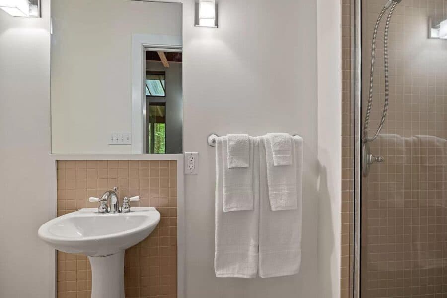 Cozy modern bathroom in a cabin at Tryon Farms community, featuring a white sink, mirror, and shower.