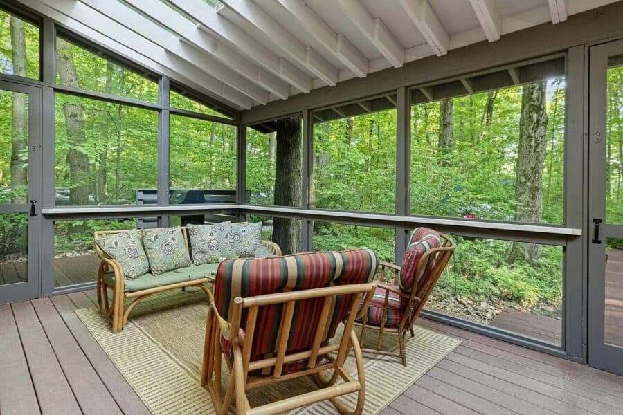 Cozy screened porch with forest views and comfortable seating.