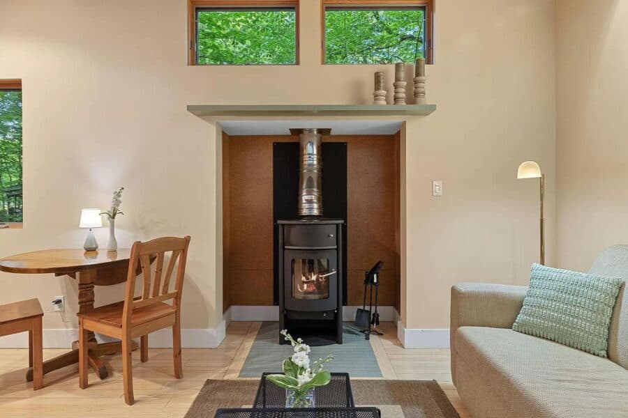 Compact cabin with wood stove and large windows.