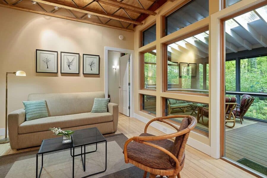 Cozy modern cabin living room with large windows, natural light, and stylish furniture in Tryon Farm.