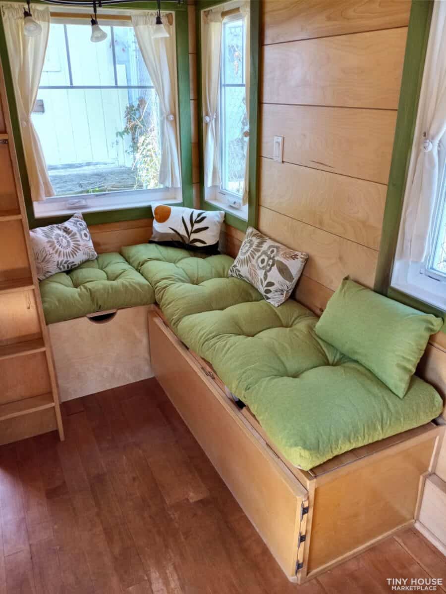 Compact tiny house interior with green cushioned seating and natural light.