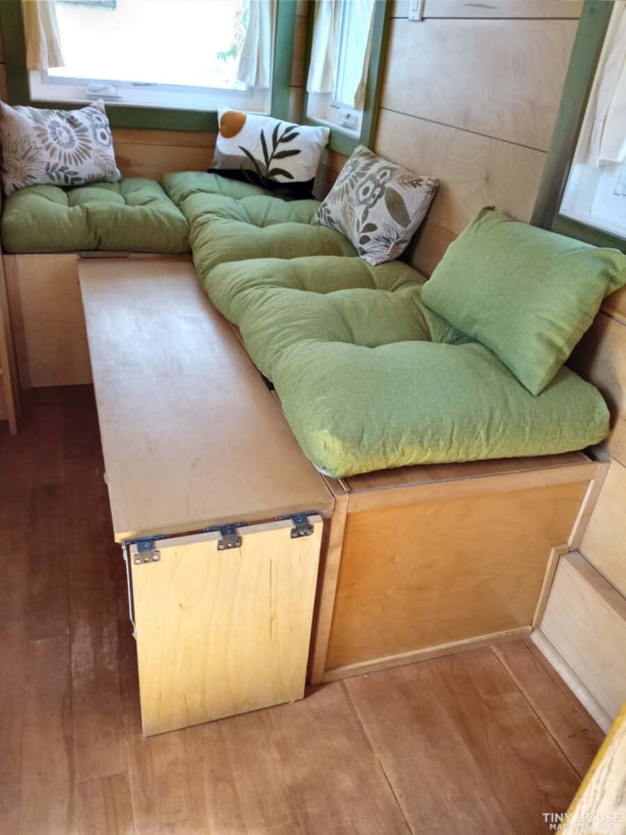 Cozy green sectional sofa inside a tiny house with decorative pillows.