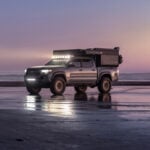 Mobile tiny house vehicle parked on beach at sunset, showcasing compact living in small spaces.