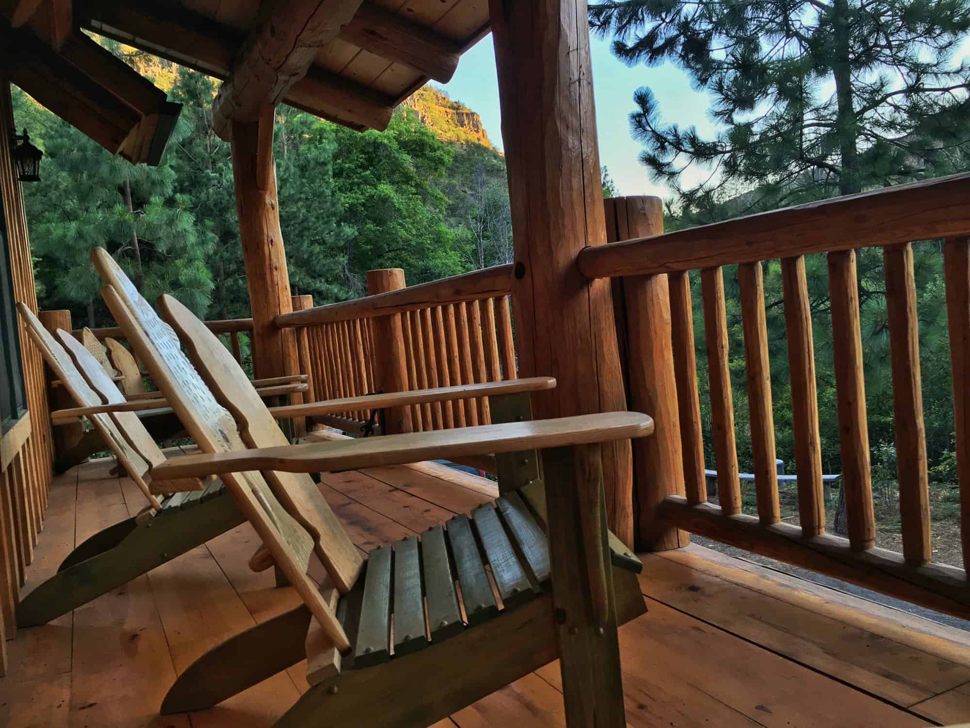 Adirondack chairs on the covered log deck of the Tygh Valley cabin overlooking the canyon