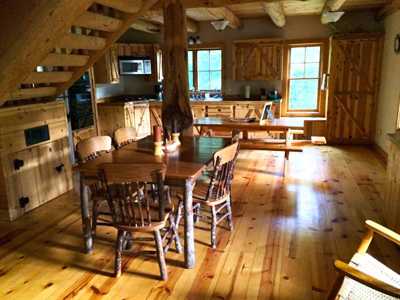 Dining area with a log post, rustic table and chairs, and pine kitchen in the Tygh Valley log cabin
