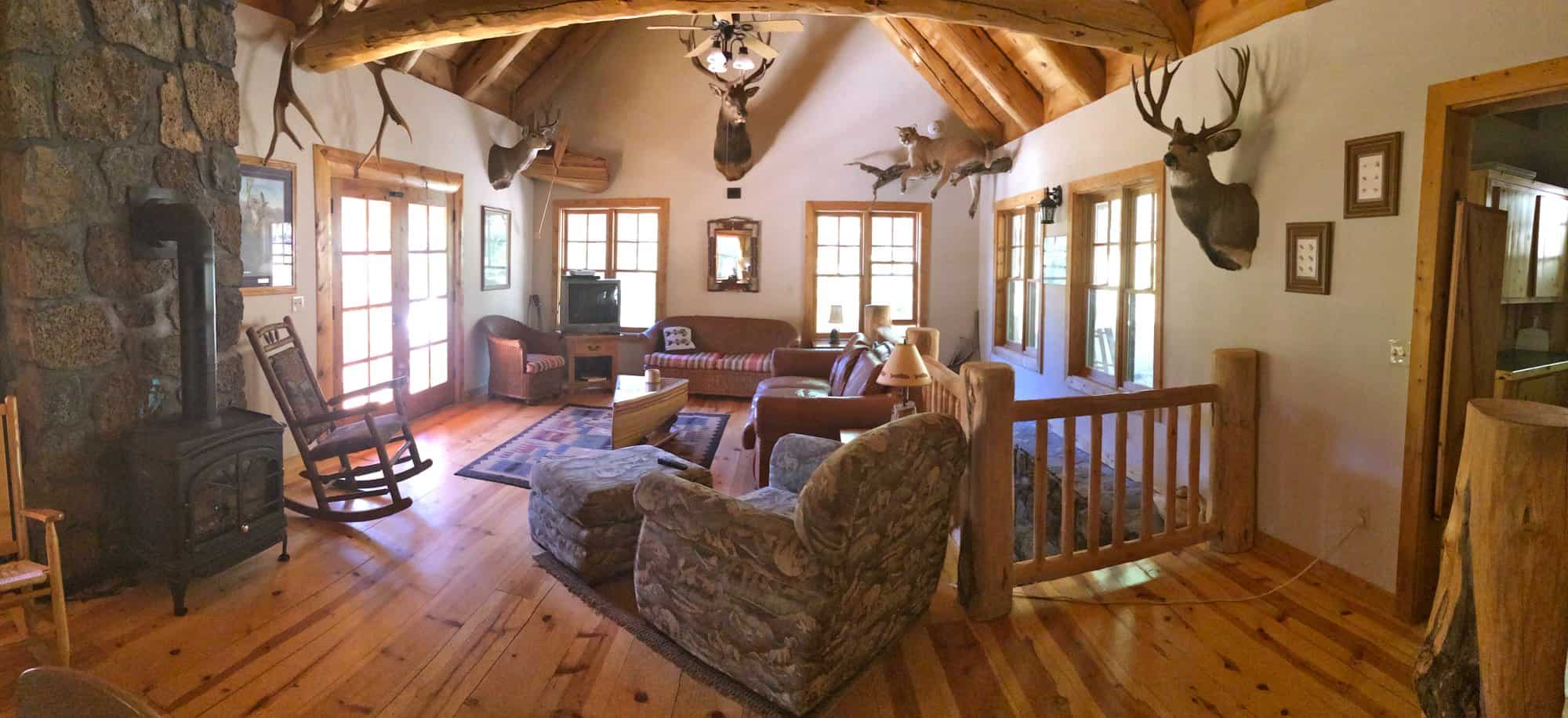Living room of the Tygh Valley log cabin with vaulted log ceiling, wood stove, rocking chair, and French doors