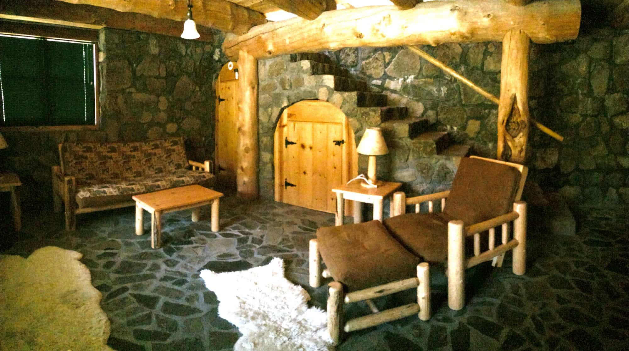 Lower-level common room with futons, log furniture, stone floor, and stone staircase