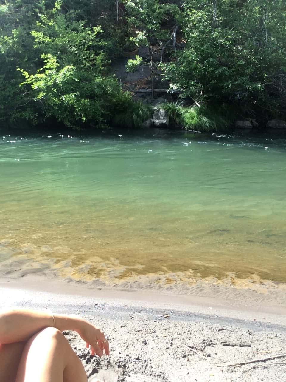 Clear green swimming hole with a sandy beach along the White River