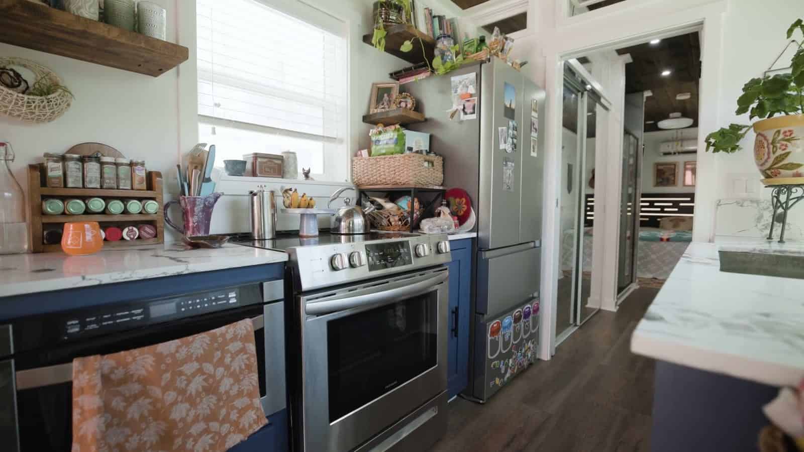 Kitchen in a container home with navy cabinets, a full-size stainless range, a stainless French-door refrigerator, and a spice rack on the counter
