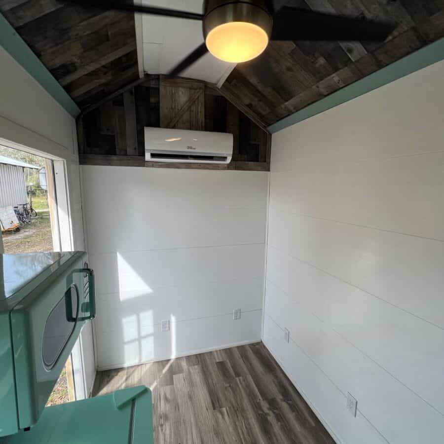Cozy tiny house interior with wooden ceiling, white walls, and natural light.
