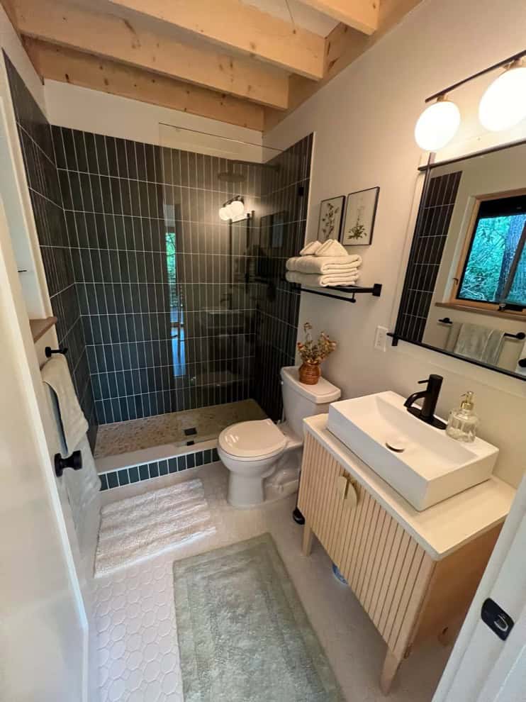 Tiny house bathroom with modern fixtures and black tile accents.