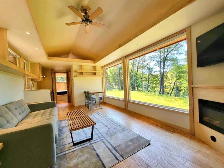 Cozy interior of a tiny house with large lakefront windows and modern furnishings.
