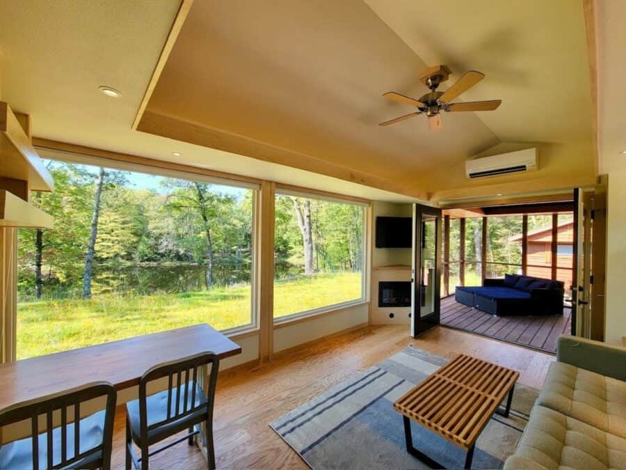 Bright lakefront tiny house living room with large windows and modern decor.