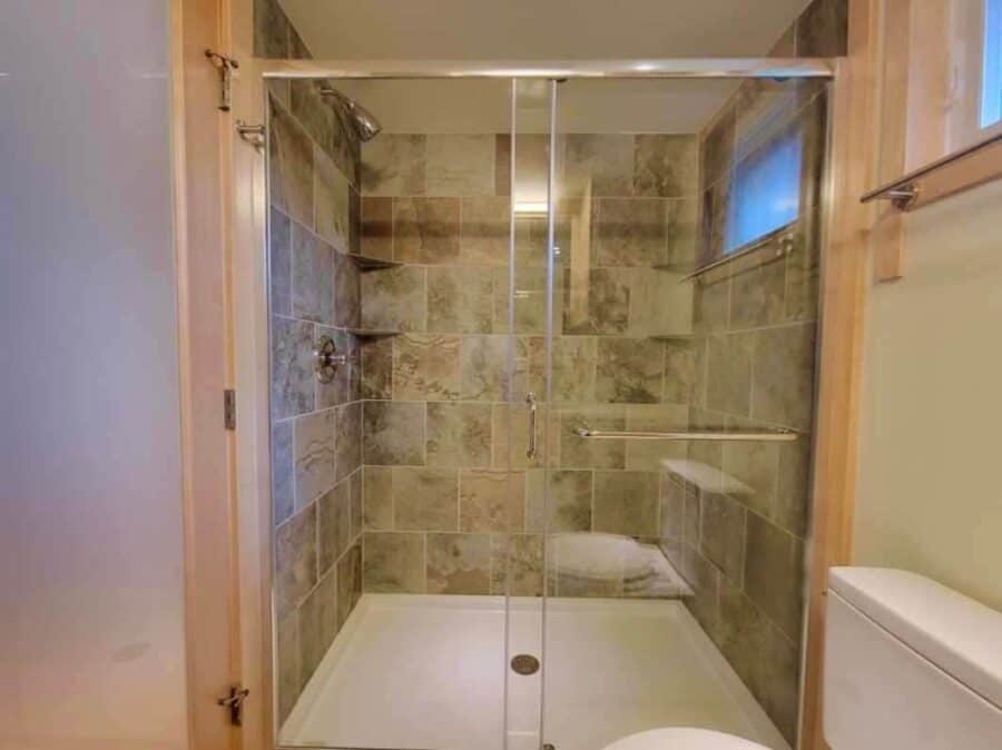 Modern tiled shower in a compact lakefront tiny house with natural light.