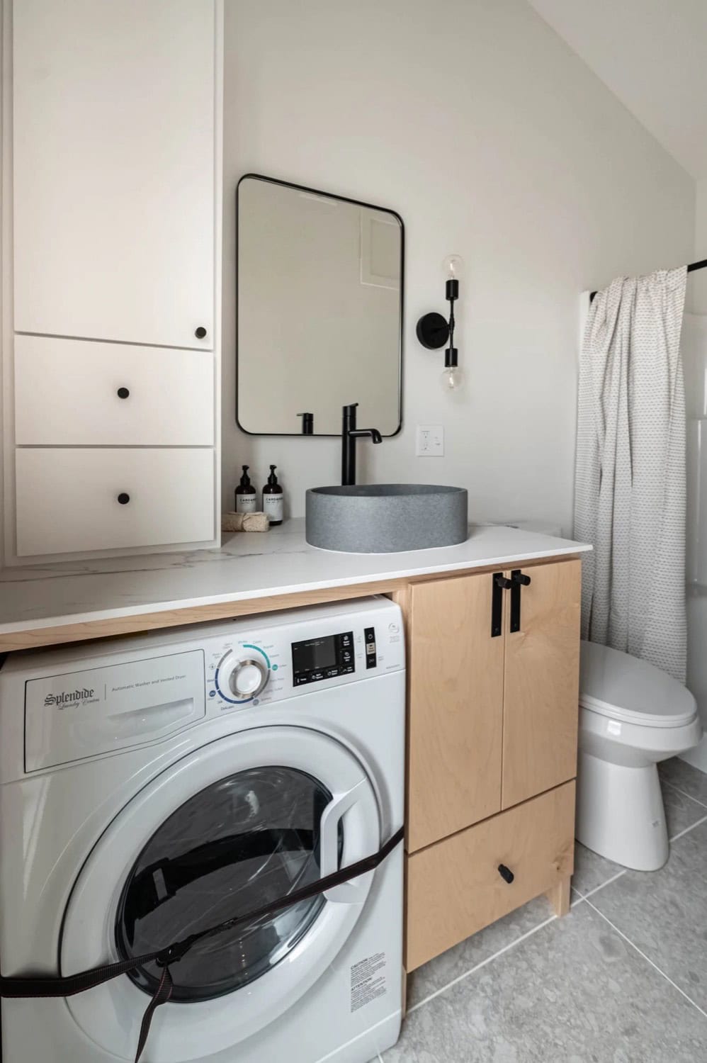 Urban Gable Park bathroom with concrete vessel sink, maple vanity and integrated washer dryer