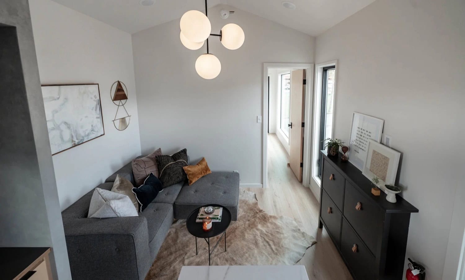 Living room in the Urban Gable Park with grey sectional, cowhide rug and black sideboard