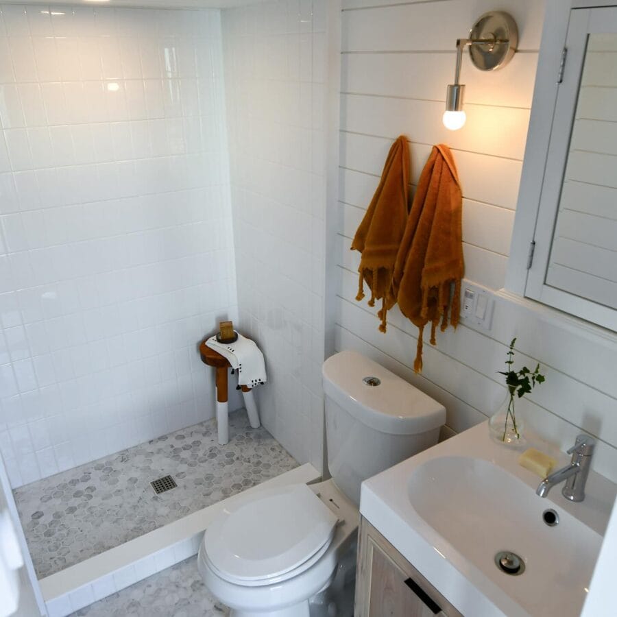 Compact bathroom in a tiny house with white walls, a small shower area, and minimalist fixtures.