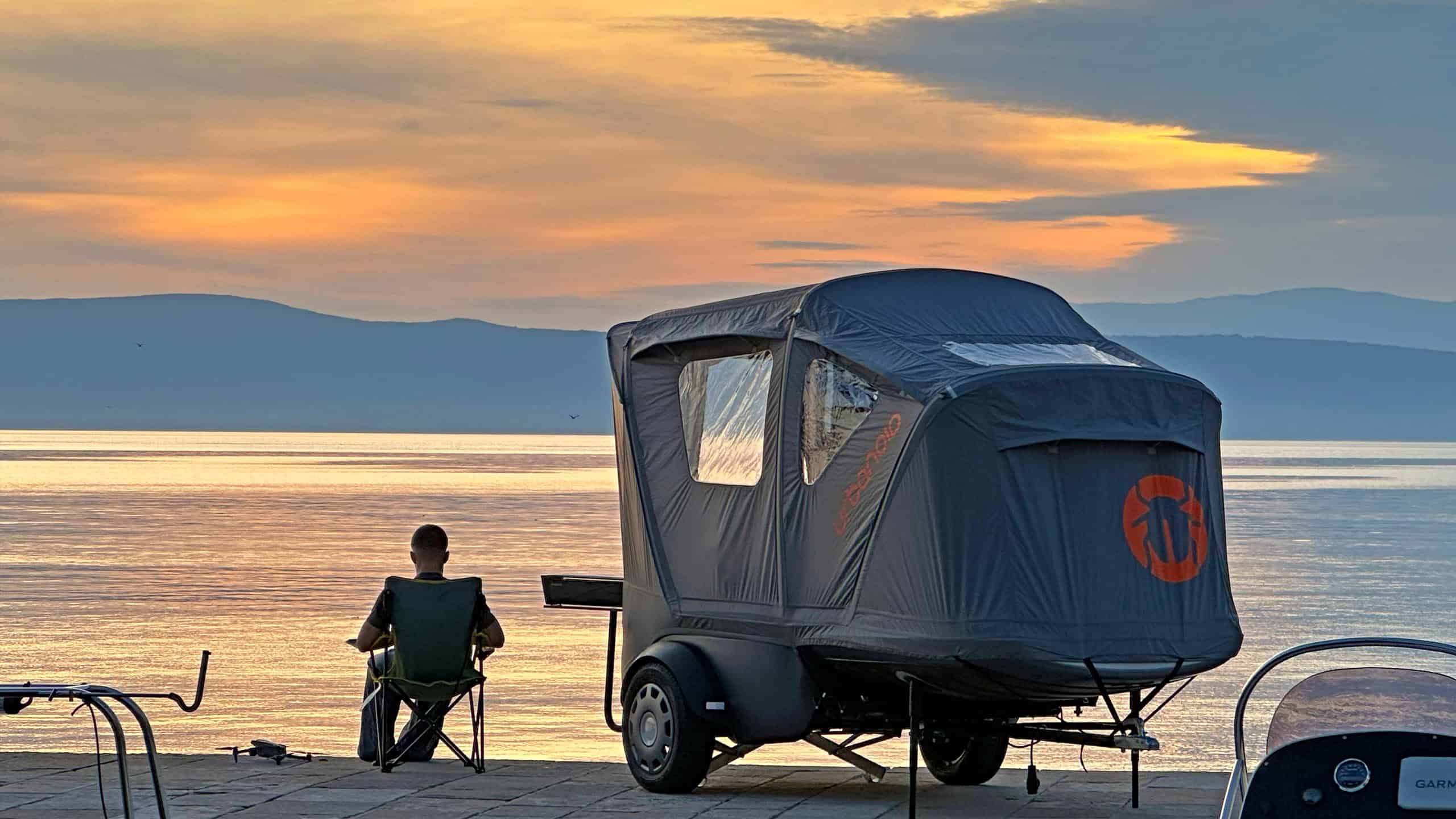 Urbanoid Booba set up at sunset by the water with a camper seated in a folding chair