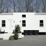 Modern 28-ft tiny house on wheels with first-floor bedroom and sleek exterior.