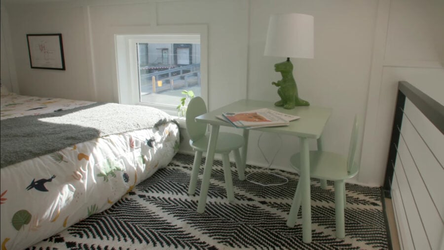Interior view of a tiny home bedroom with a bed, small desk, and playful decor.