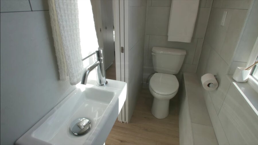 Compact tiny house bathroom with sink and toilet in a small space.