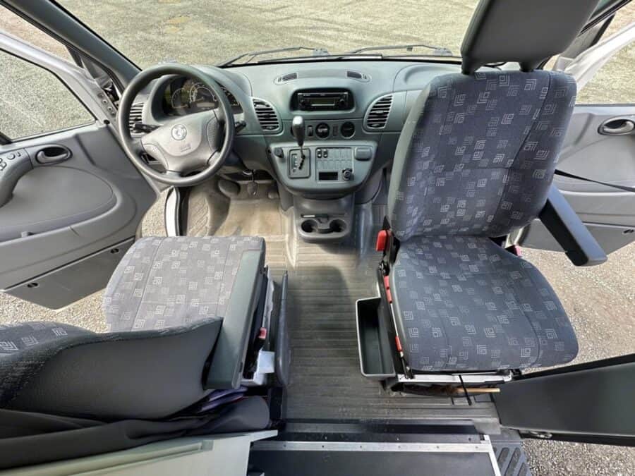 Interior view of a minimalist van with CNC-milled wood and solar setup.