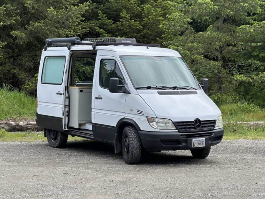 Compact van interior with CNC-milled features, 200W solar system, and sleek minimalist kitchen desig.