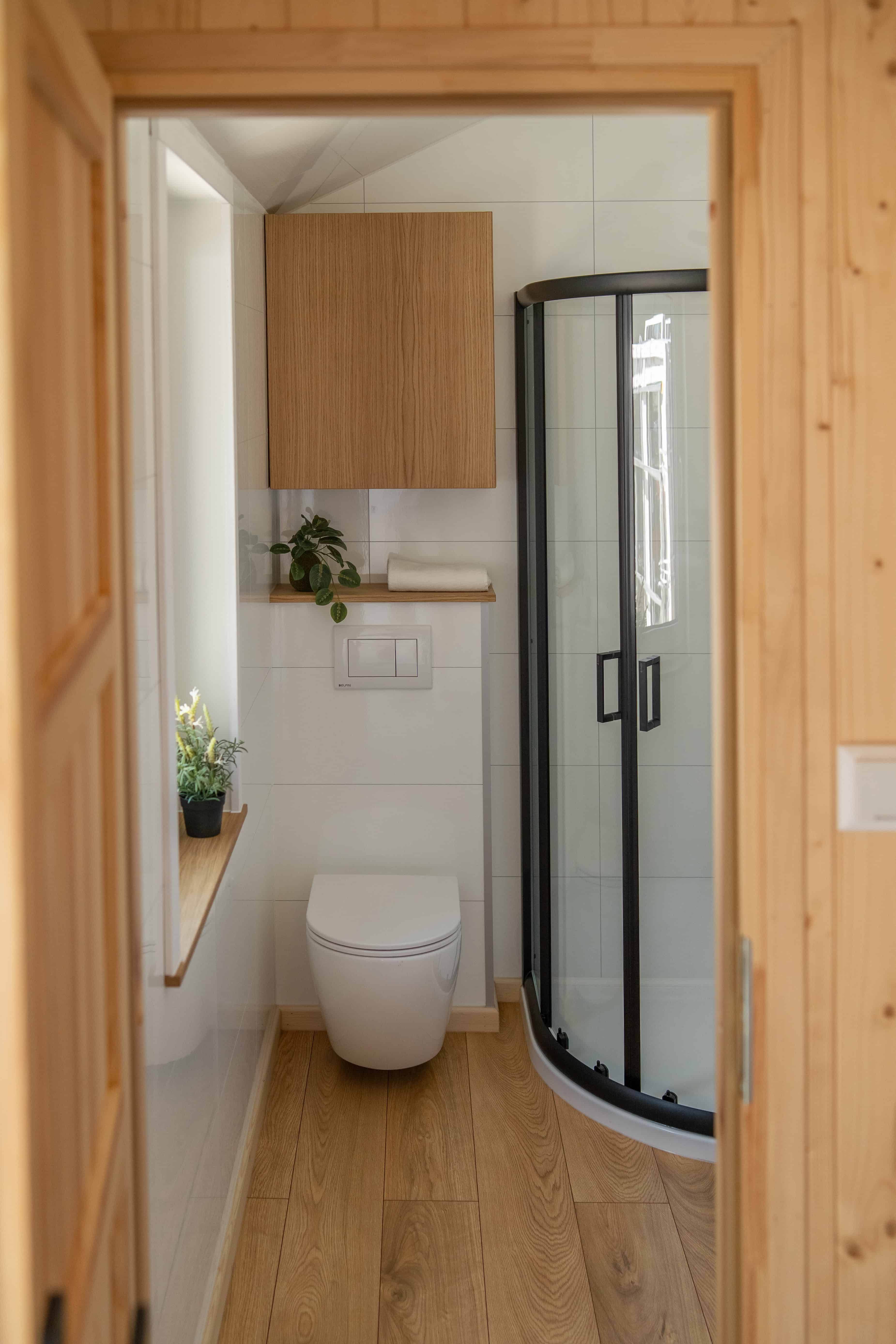 The Vagabond Haven Evergreen bathroom with a corner shower cabin, wall-hung toilet, and wood-topped vanity