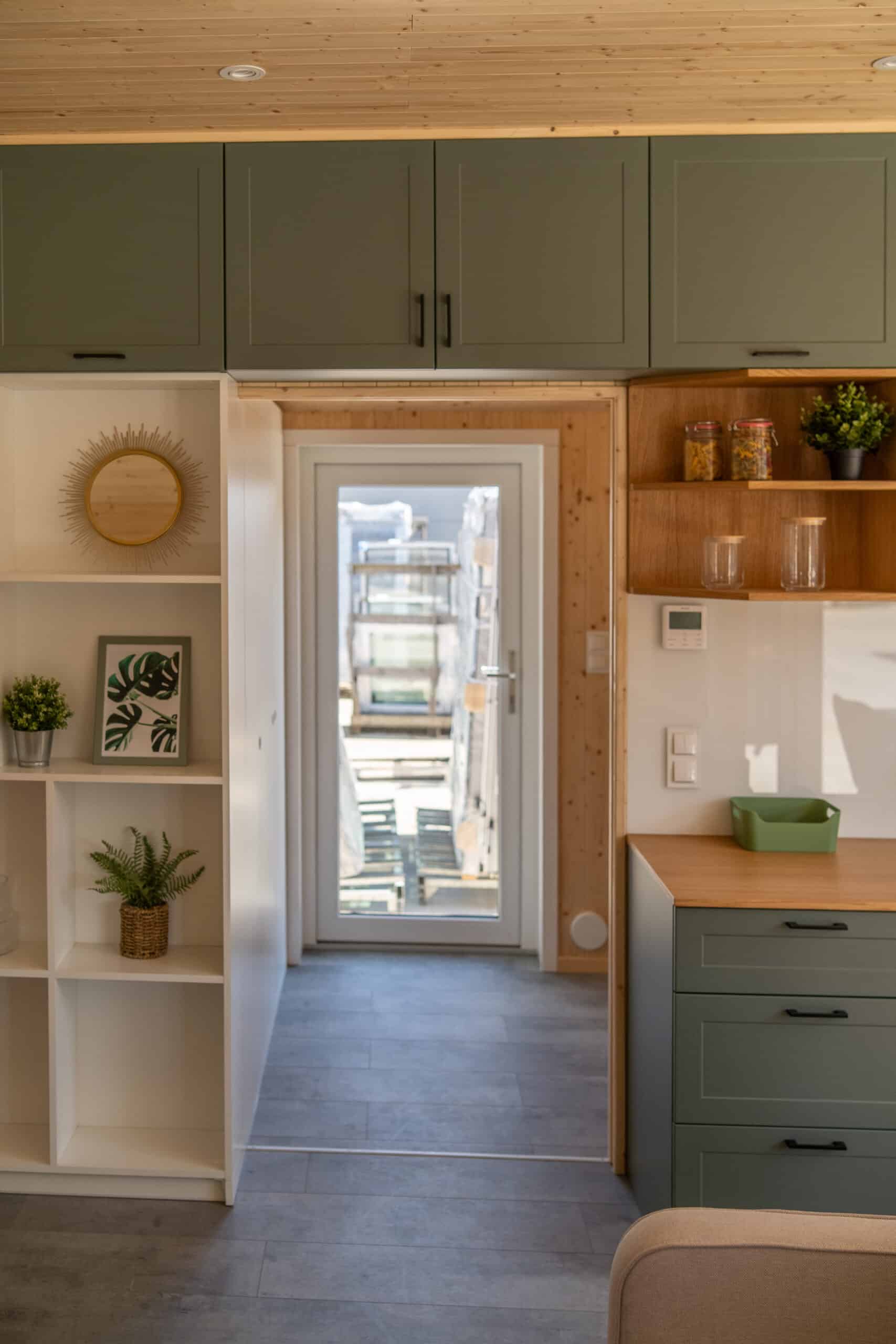 The entrance and kitchen of the Vagabond Haven Evergreen with a glass door and control panel