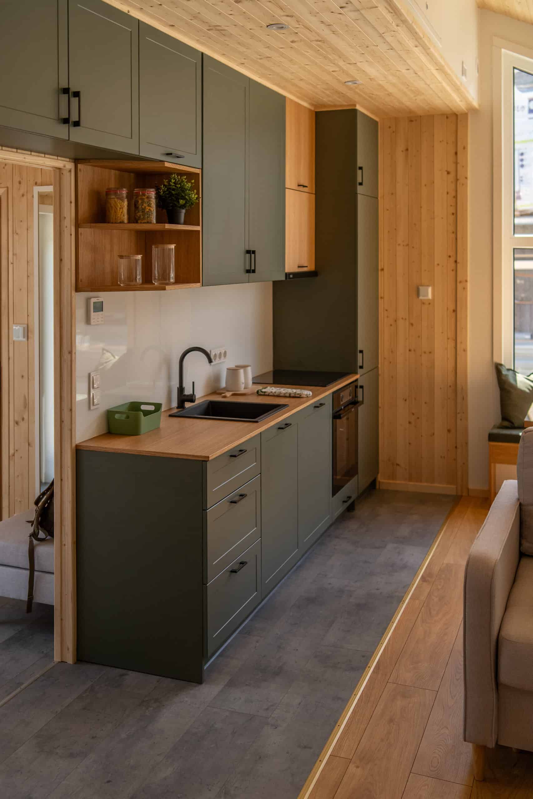 The Vagabond Haven Evergreen kitchen with sage-green cabinets, oak counters, induction cooktop, and a built-in oven