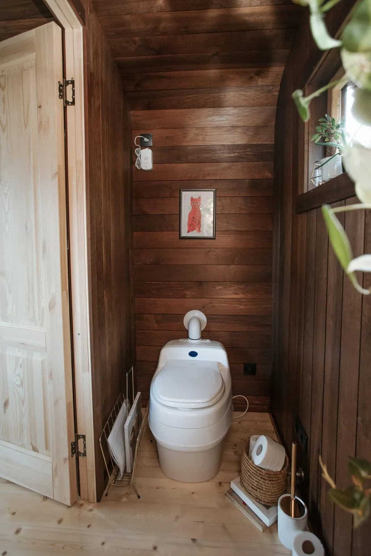 The Nature Pod's wood-paneled bathroom with a white Separett dry toilet