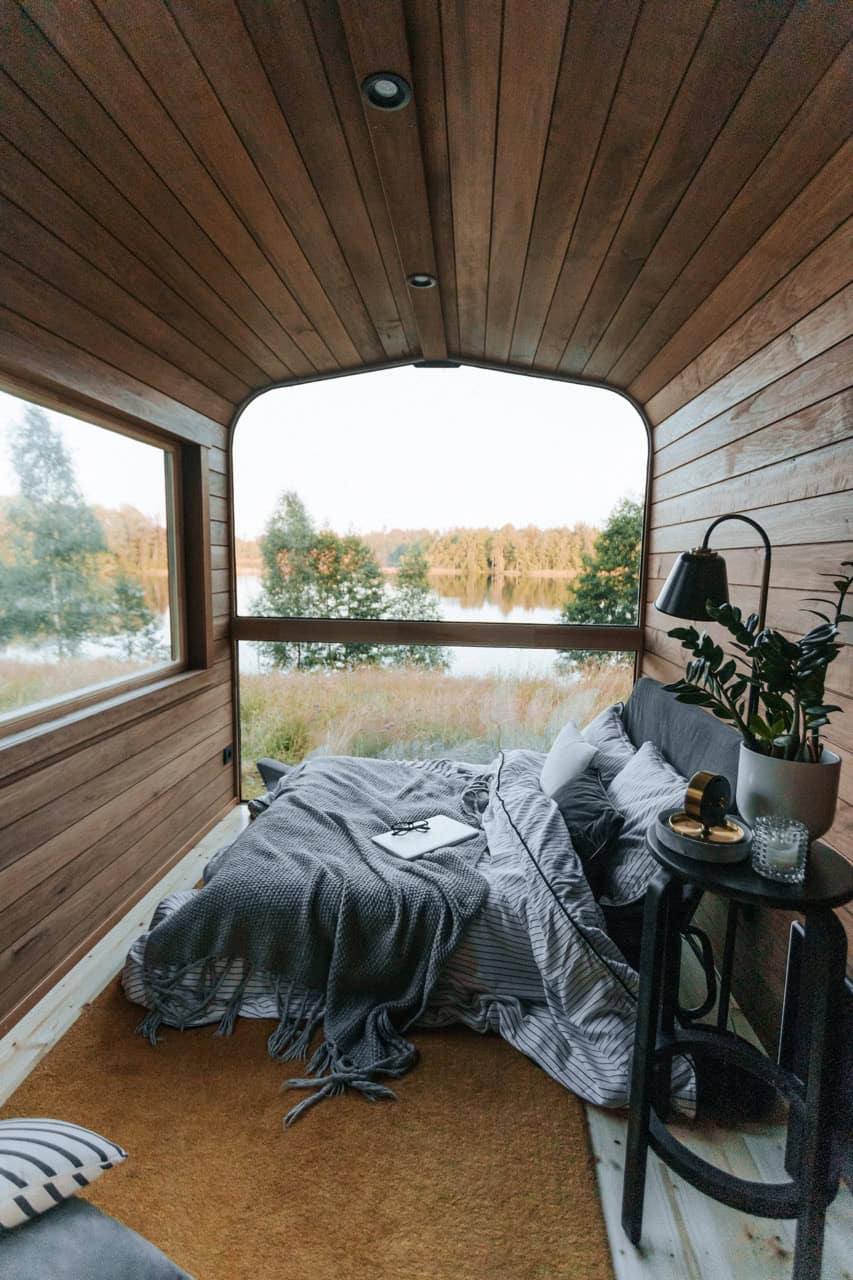 The Nature Pod bedroom with a queen bed facing the panorama window and a lake view