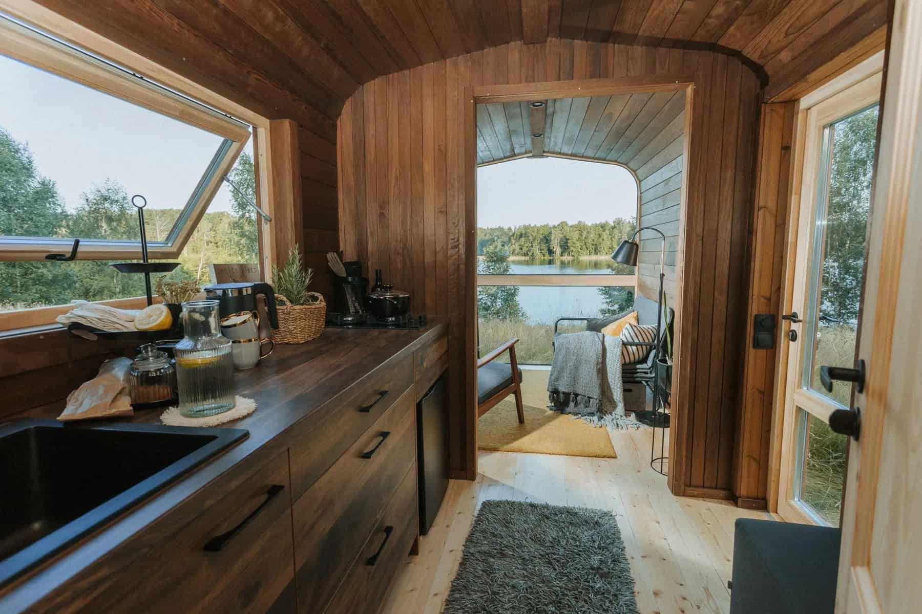View down the length of the Nature Pod from the kitchen counter to the bed and panorama window at the far end