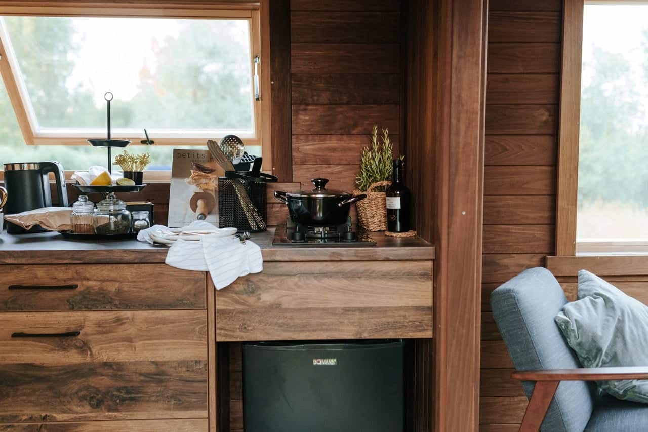 The Nature Pod kitchen with a timber counter, cooktop, under-counter fridge, and an openable window