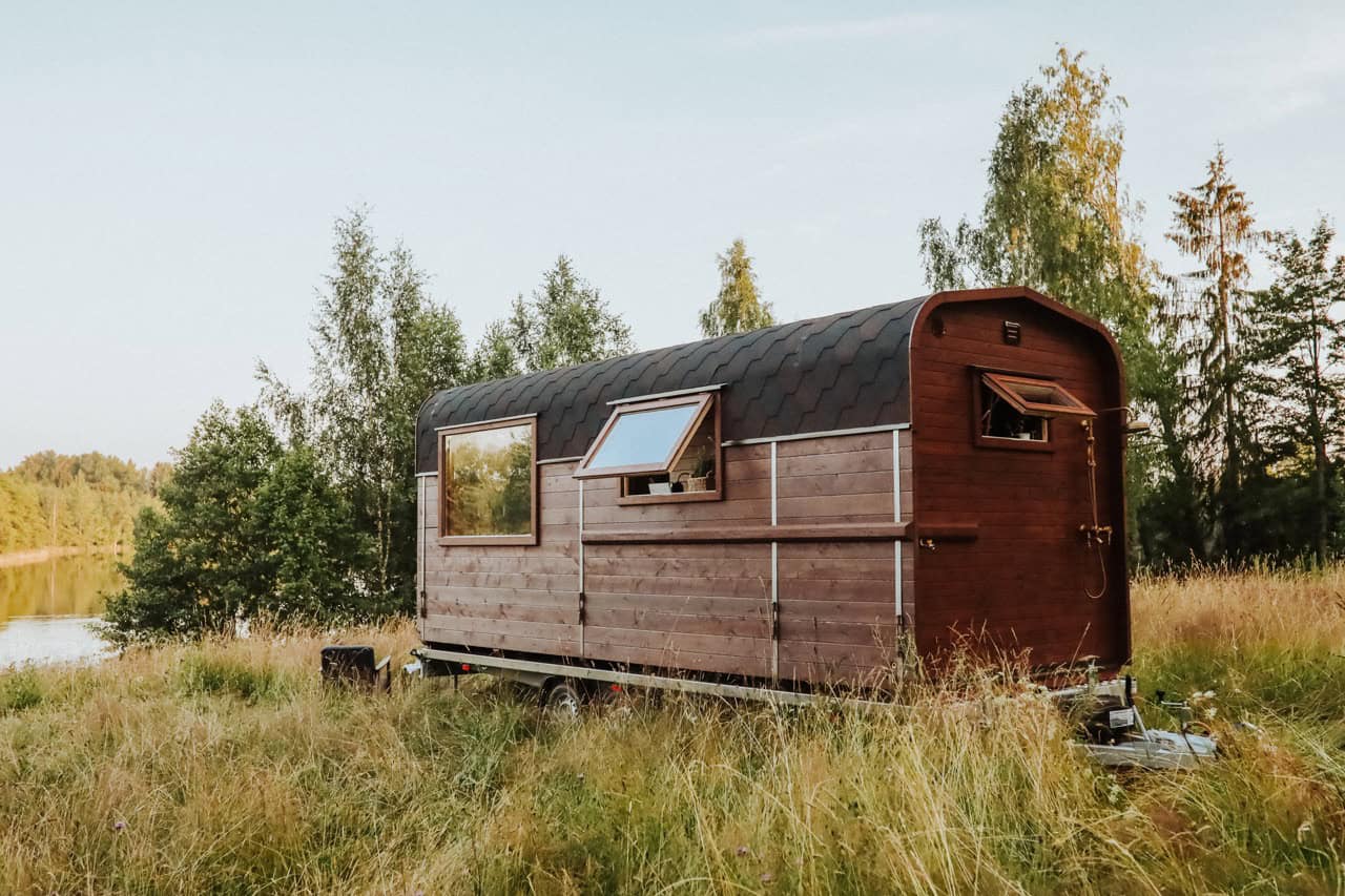 The Nature Pod's curved ThermoWood profile with openable windows, set beside a lake