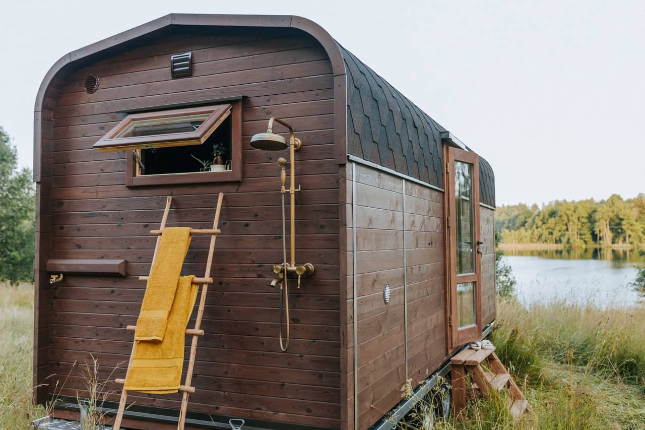 The brass outdoor shower and wooden ladder mounted on the side of the Nature Pod