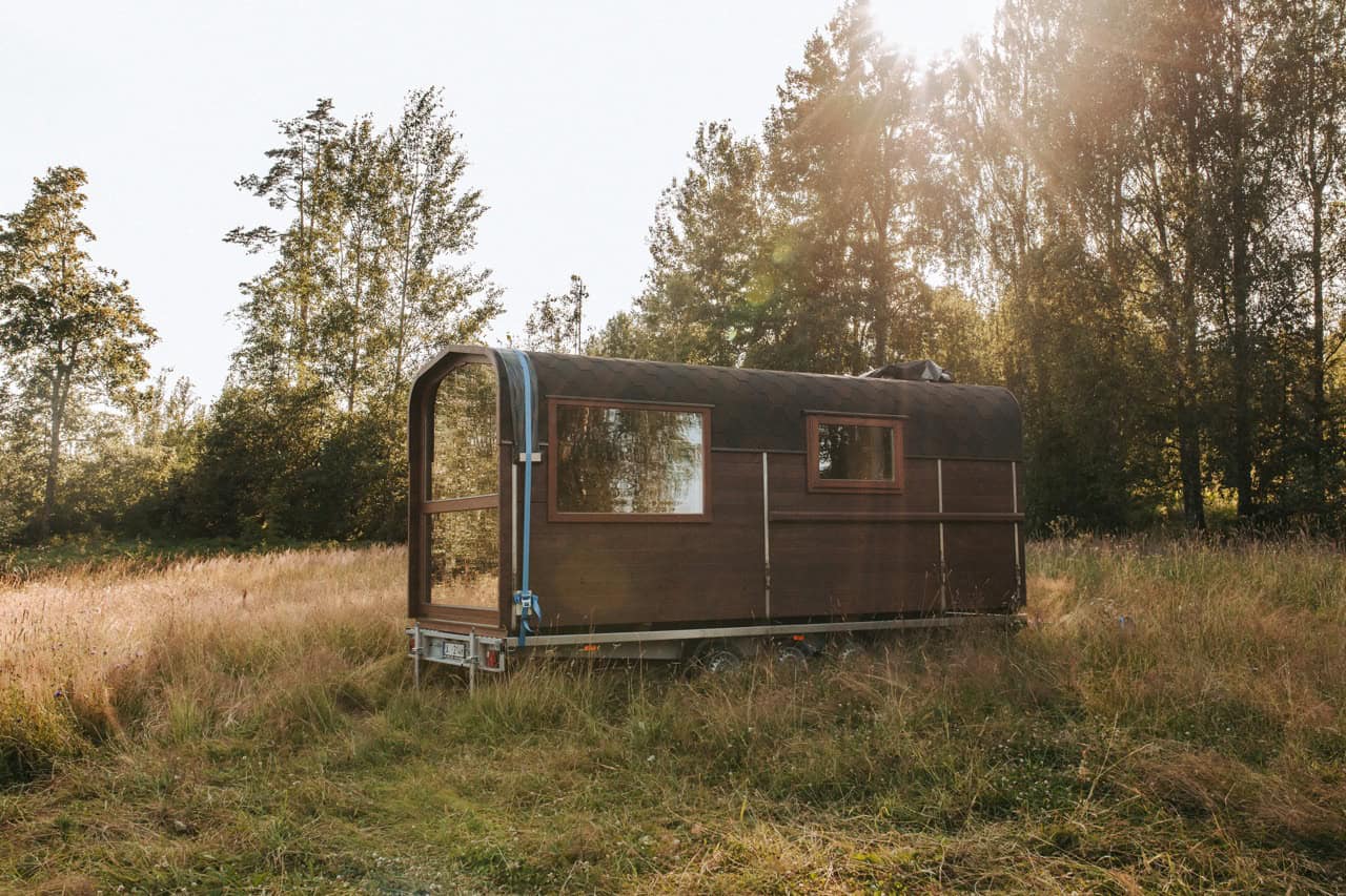 The Nature Pod glowing at sunset in a meadow, its large windows lit from within