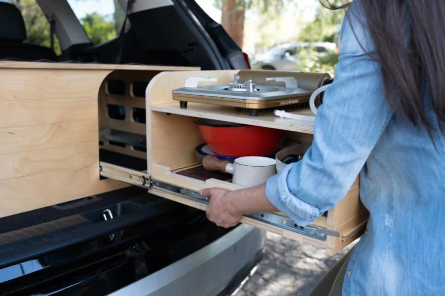 Compact SUV conversion kit for tiny house living, featuring efficient kitchen storage solutions.