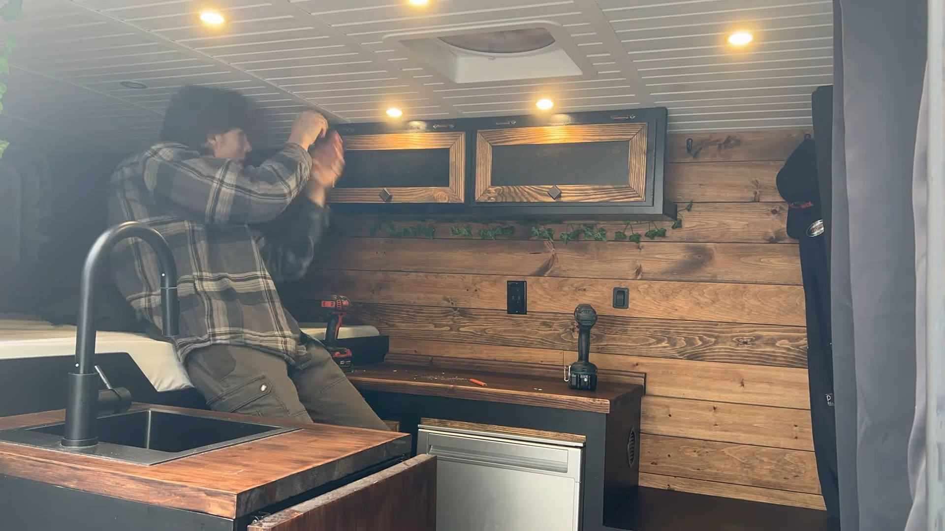 Finished galley with a black faucet, sink, compact fridge, and wood-plank shiplap walls