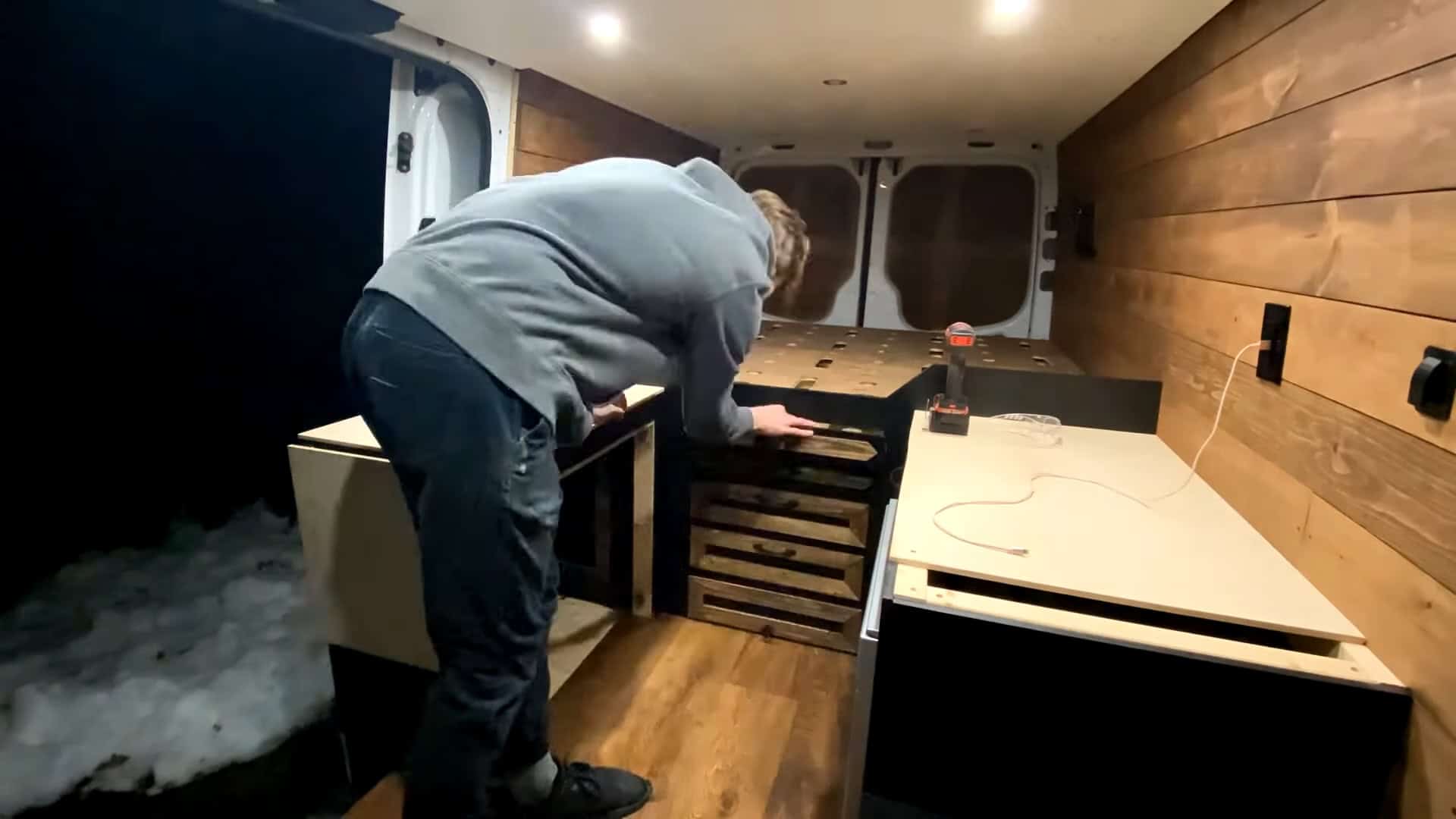 Building the galley with wood-front drawers and a butcher-block counter, snow outside the open door