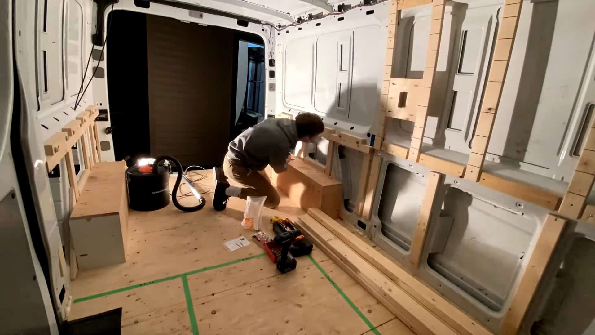 Wood furring strips and plywood bench framing taking shape inside the van build