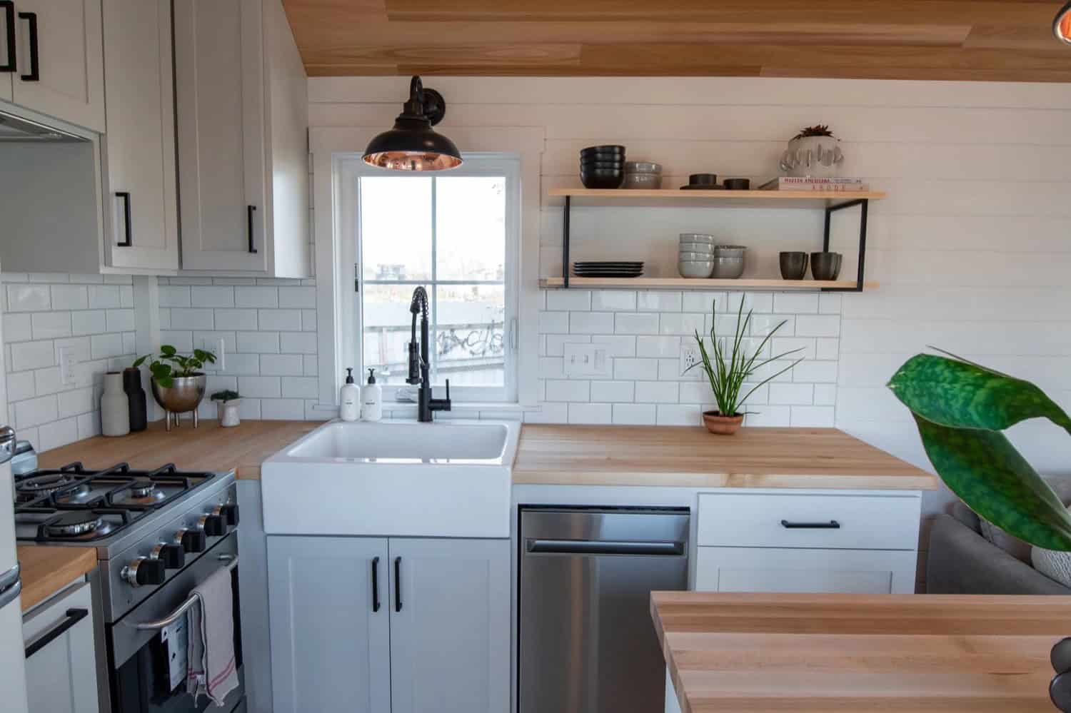Villa Max kitchen wall with gas range, farmhouse sink, butcher-block counters and subway tile backsplash