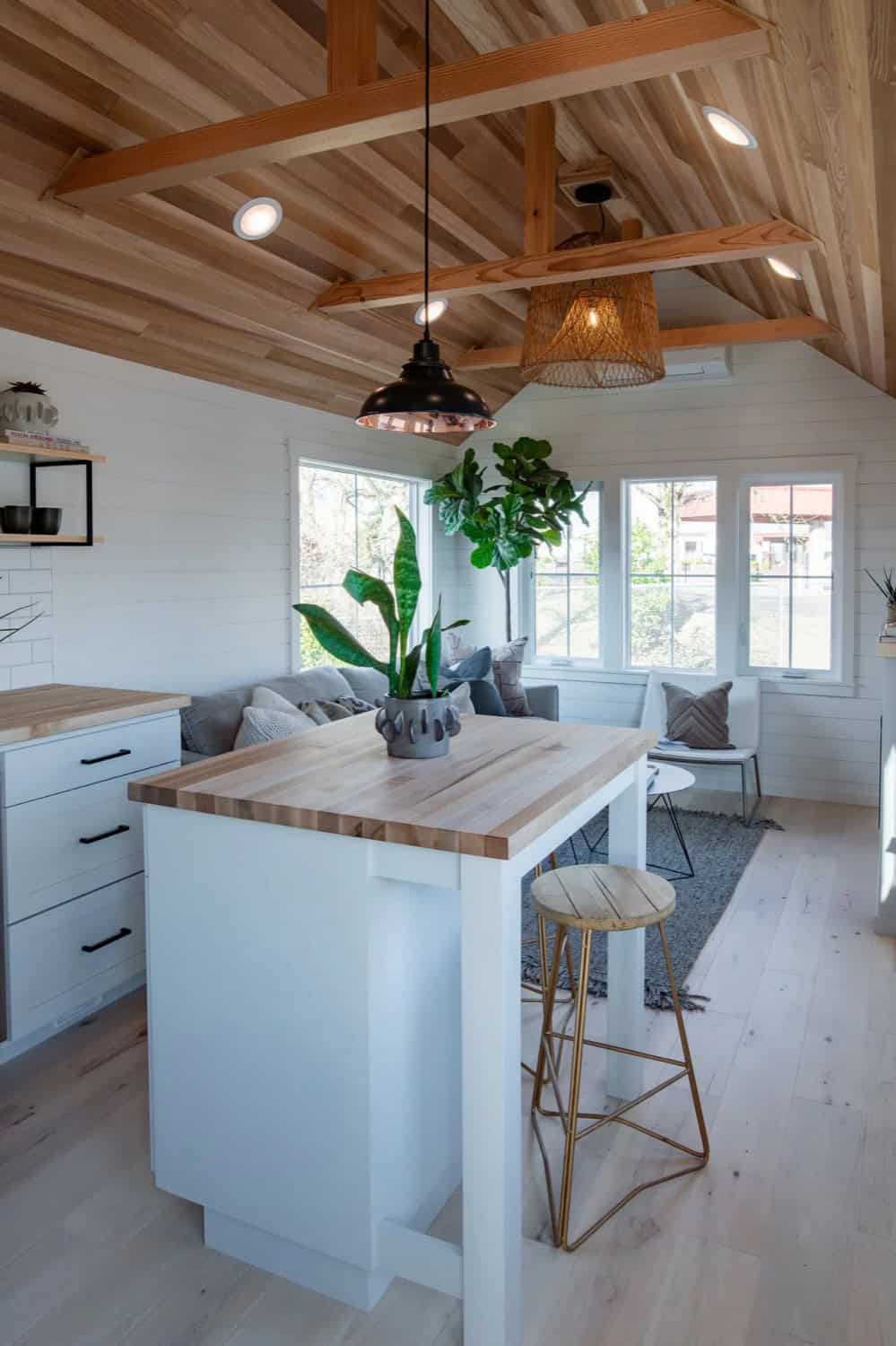 Open living and dining area in the Villa Max with vaulted wood ceiling, large windows and grey sofa