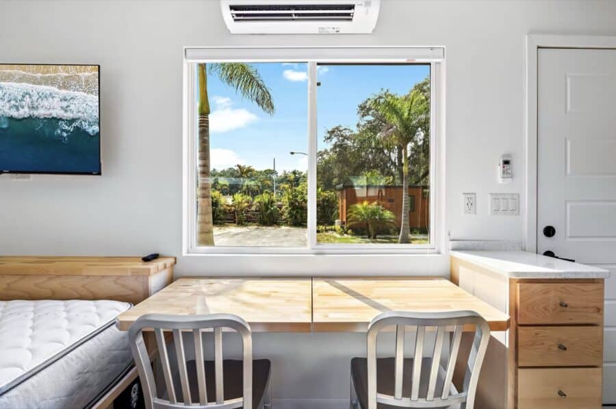 Cozy tiny house interior with large window overlooking tropical garden in Florida.
